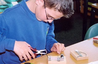 Young boy wiring an electrical device in a classroom