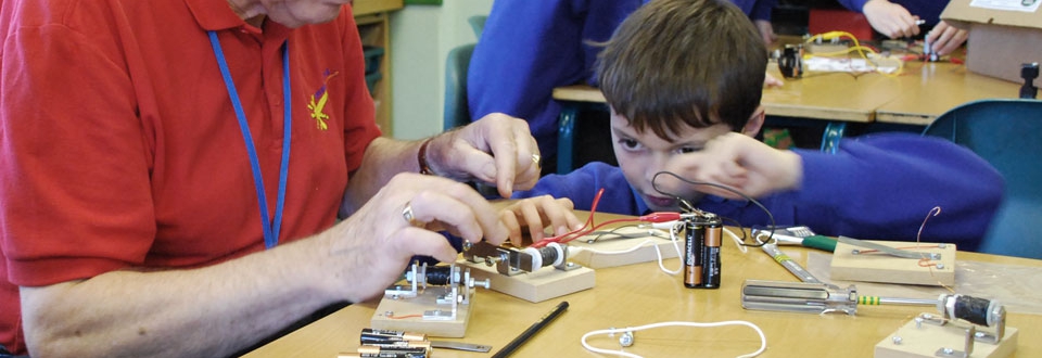 Young boy wiring a morse code buzzer with a teacher