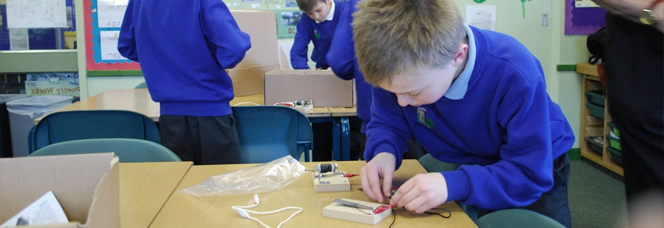 Young boy wiring up an electrical device in a classroom