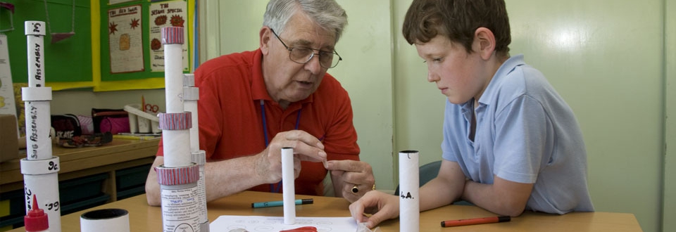 Teacher showing a young boy how the lense fits into the tubes of a telescope