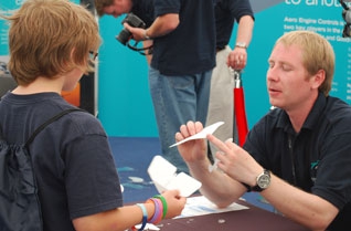 Teacher demonstrating a paper aeroplane to a young boy