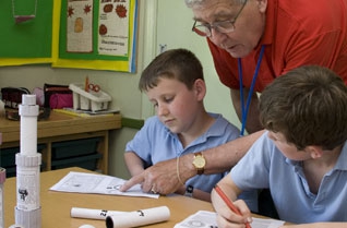 Teacher showing two boys how to make a telescope