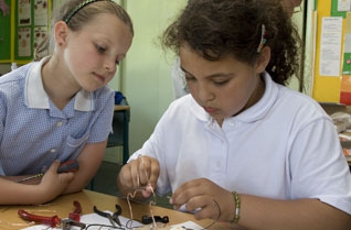 Two young girls building a wire buzzer game