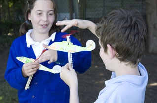Young girl and boy winding the rubber bands on model helicopters
