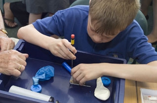 Boy screwing an electrical block with a screwdriver