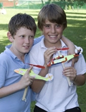 Two young boys holding rubber band powered model helicopters