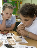 Two young girls making a buzzer game in a classroom