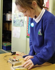 Young girl using a morse key buzzer in a classroom
