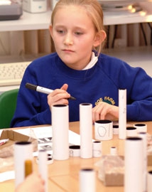 Young girl making a cardboard tube telescope in a classroom